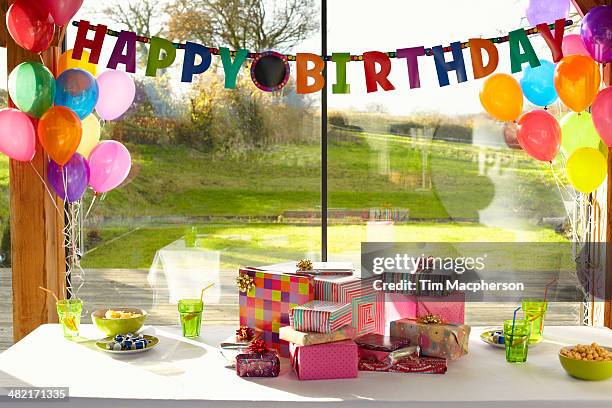 table laid with birthday gifts and balloons - regalos de aniversario fotografías e imágenes de stock