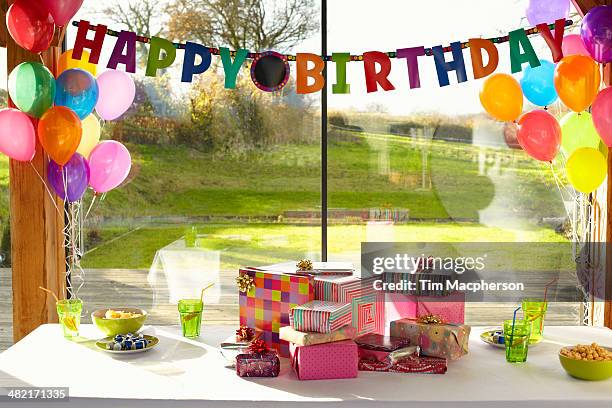 table laid with birthday gifts and balloons - birthday present stock pictures, royalty-free photos & images