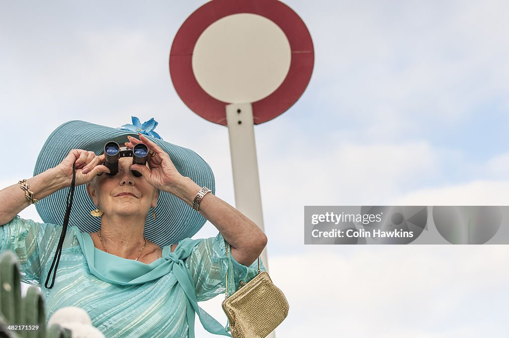 Senior woman at races looking through binoculars