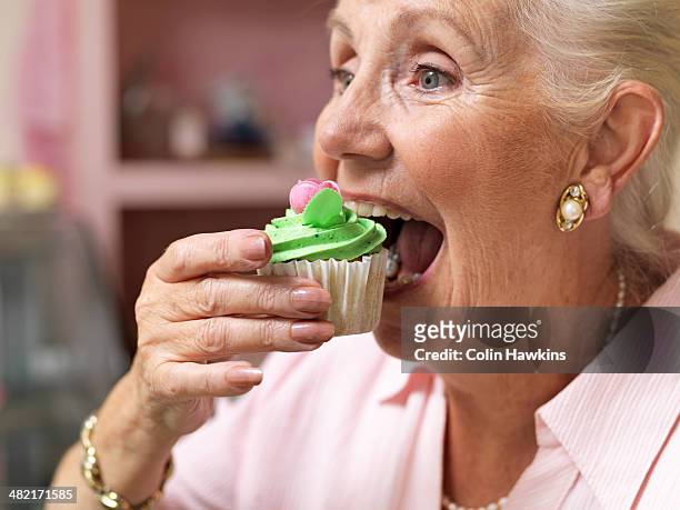 senior woman enjoying cupcake in cafe - cake face imagens e fotografias de stock