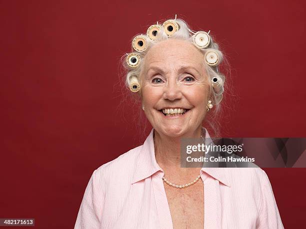 studio portrait of senior woman in hair rollers - hair curlers stock-fotos und bilder