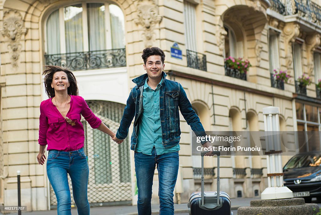 Young couple walking with wheeled suitcase, Paris, France