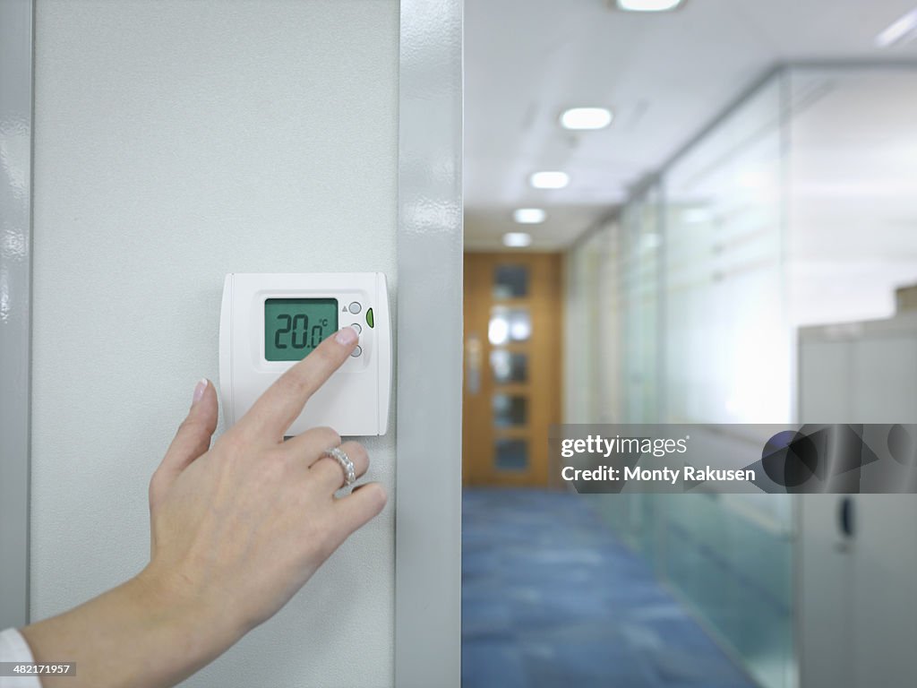Close up of office worker adjusting thermostat