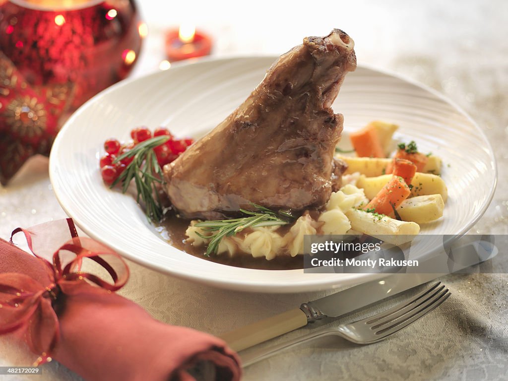 Slow cooked lamb shank with fresh rosemary, carrots, potatoes, Italian beans, white wine and garlic among festive decorations