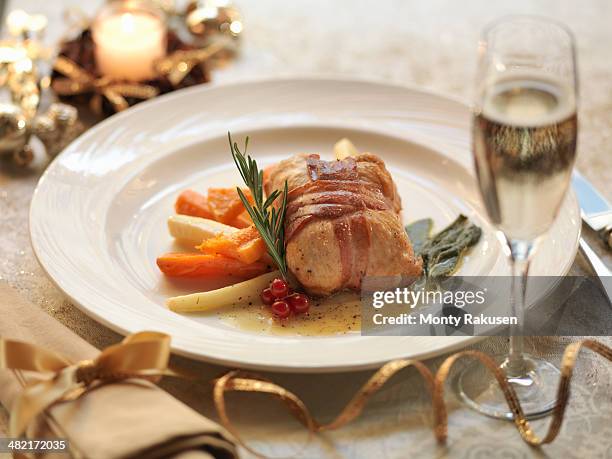 turkey parcel wrapped in pancetta, stuffed with cranberry and orange and served with lemon and sage sauce with roasted winter vegetables, amid festive decorations - main course stock pictures, royalty-free photos & images