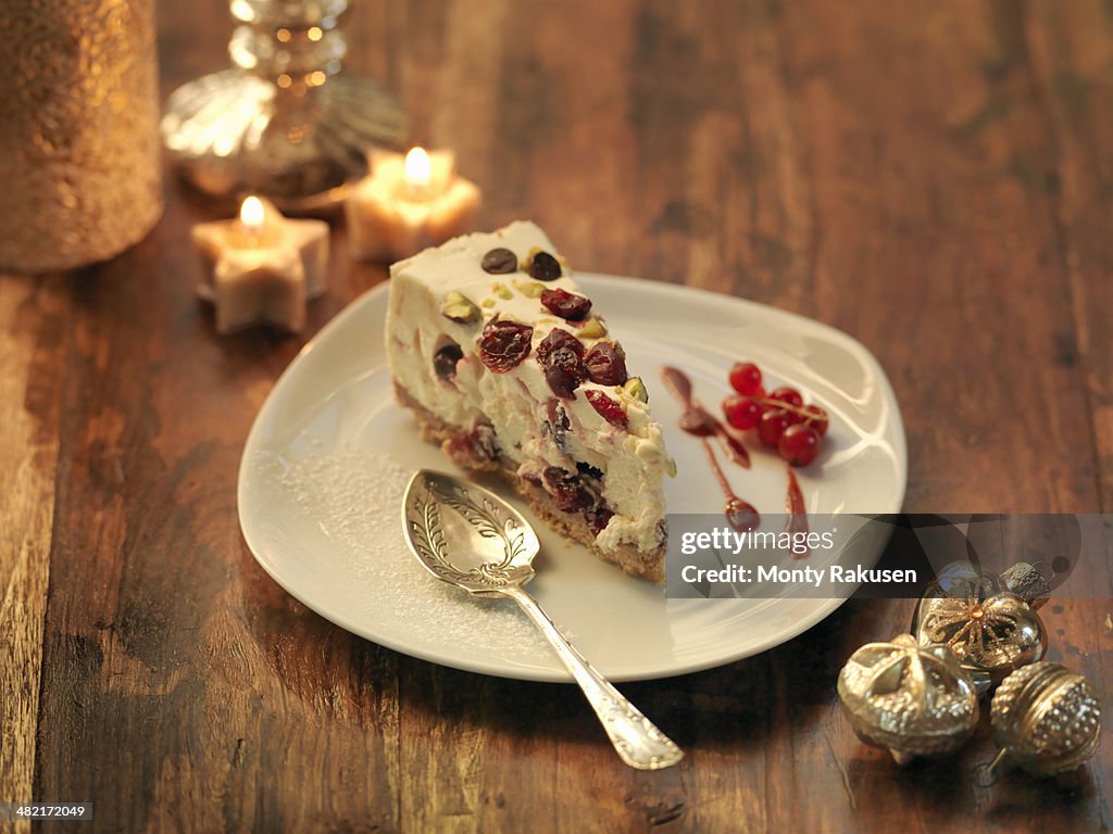 Mascarpone cheesecake with cranberry, pistachio, orange zest and chocolate chip amongst festive decorations