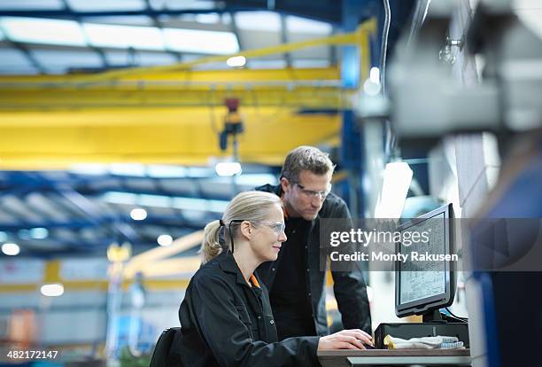 engineers using computer to work on plans in engineering factory - computer aided manufacturing stock pictures, royalty-free photos & images