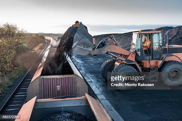 diggers loading coal onto train at surface coal mine at dawn - coal mine 個照片及圖片檔