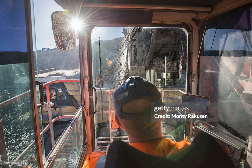 Excavator driver in digger cab at surface coal mine