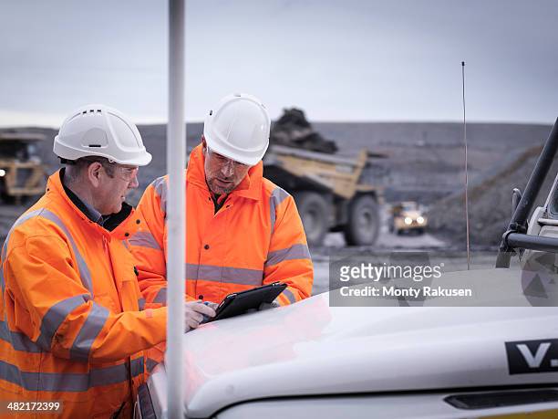 geologists discuss plans on digital tablet in surface coal mine - mine worker stock pictures, royalty-free photos & images