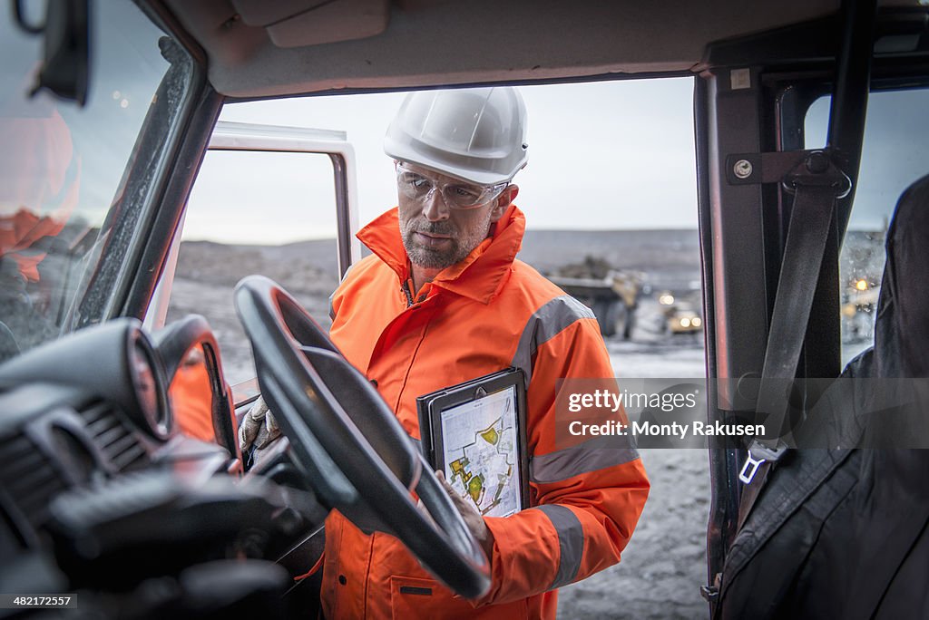 Geologist holding digital tablet in truck in surface coal mine