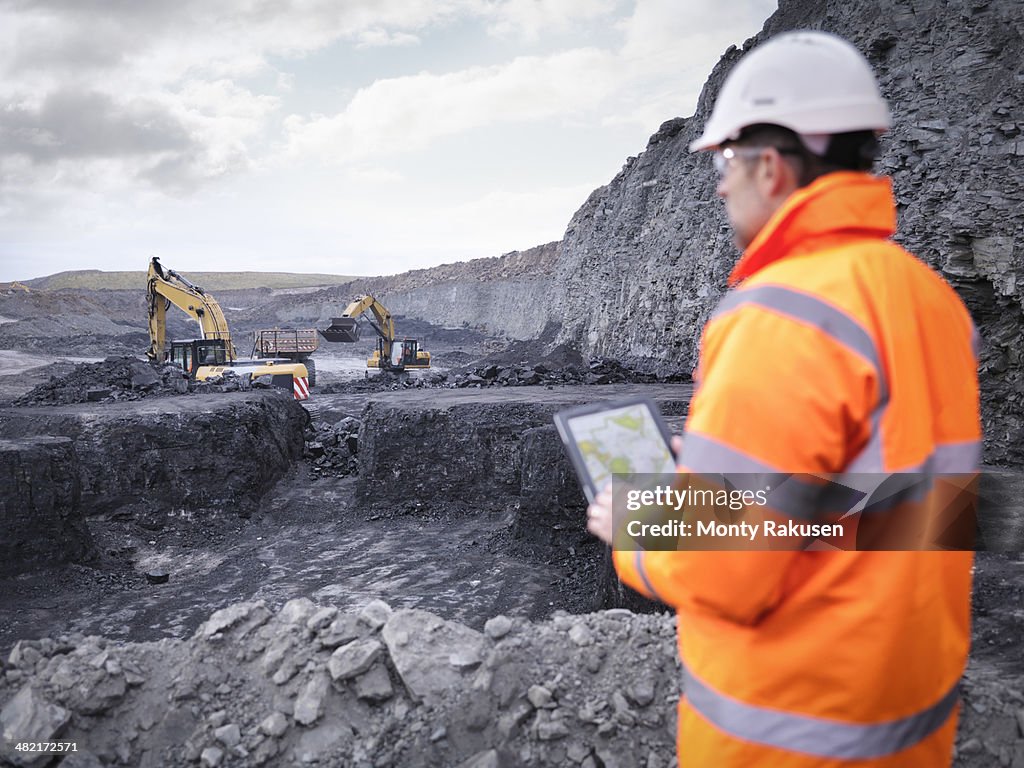 Miner checks plans on digital tablet in surface coal mine