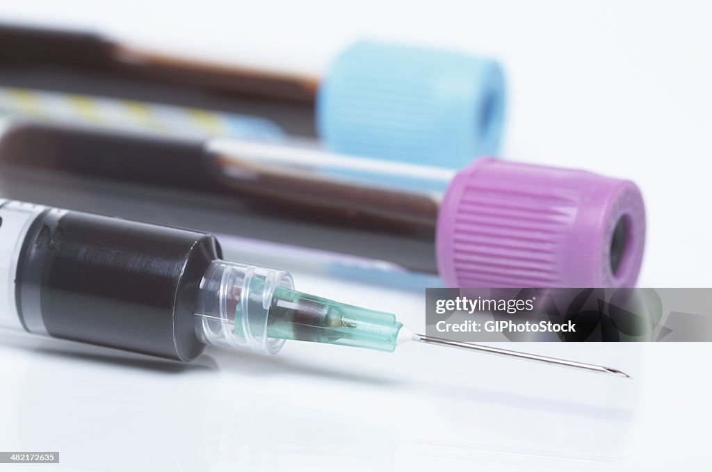 Disposable plastic medical syringe and color coded tubes containing synthetic blood samples. Blue top - buffered sodium citrate. Lavender top - K2-EDTA anticoagulant