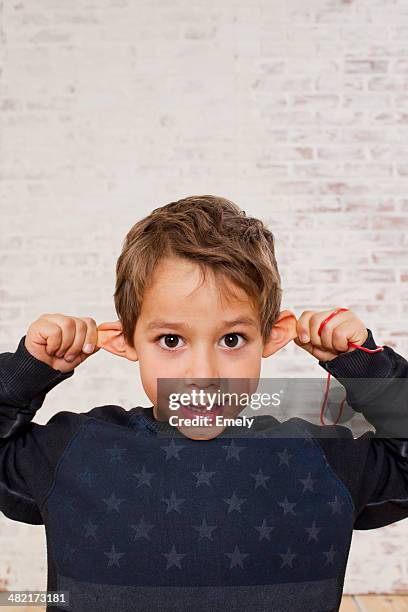 studio portrait of boy pulling his ears - ear pulling stock pictures, royalty-free photos & images