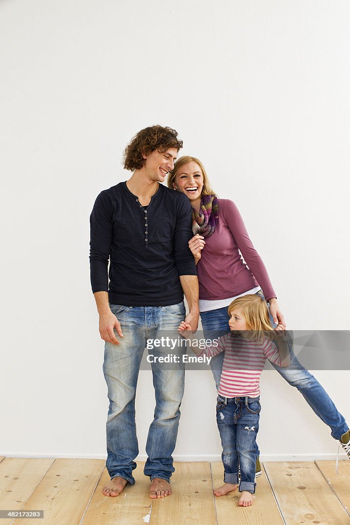 Studio shot of couple holding hands with young daughter