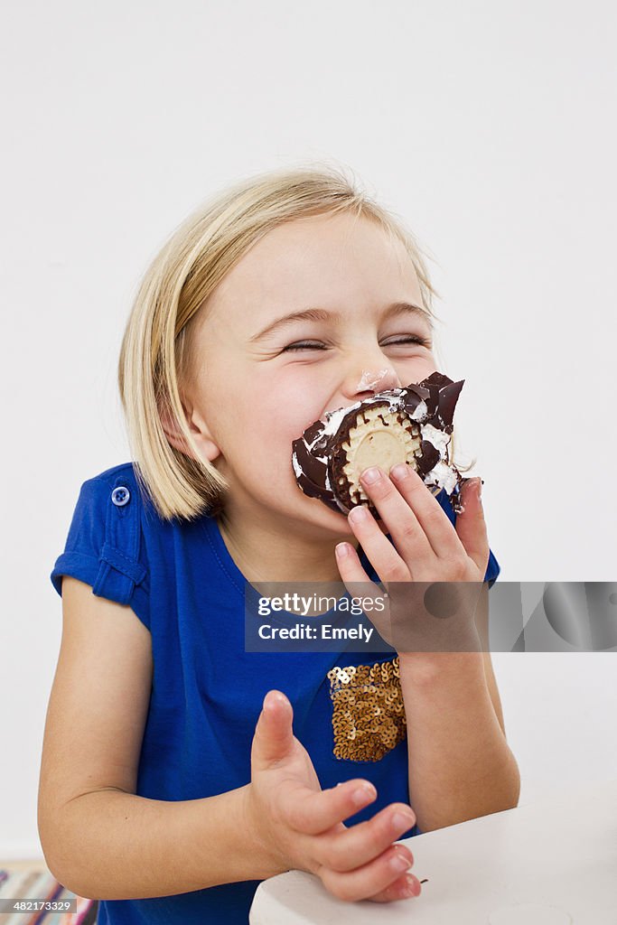 Studio portrait of young girl eating chocolate marshmallow