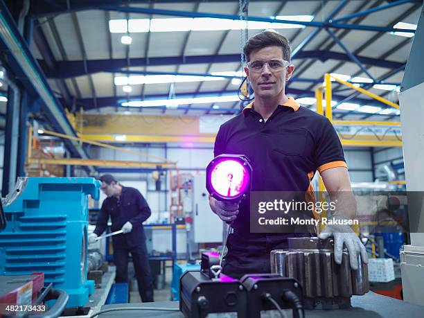 engineer using ultraviolet light to test for cracks in gear wheel, portrait - engineer gearwheel factory stockfoto's en -beelden