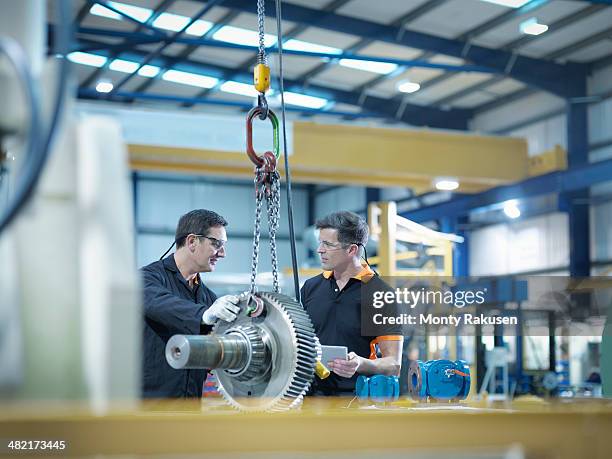 engineers with gear wheel at work station in factory - engineer gearwheel factory stockfoto's en -beelden