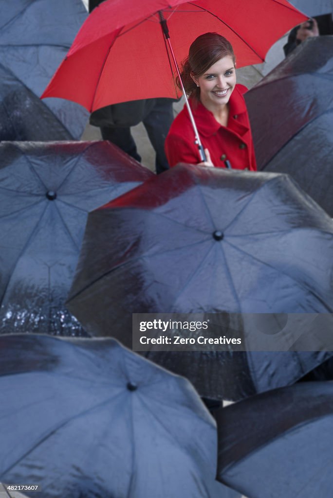 Young woman with red umbrella amongst black umbrella's