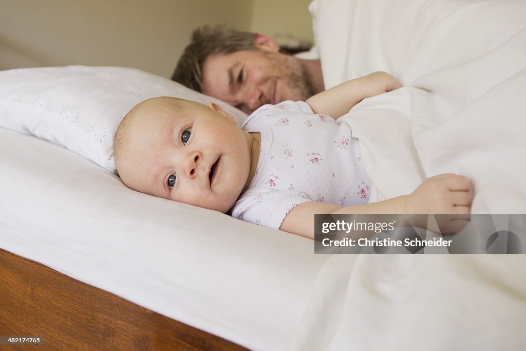 Father and baby daughter on bed