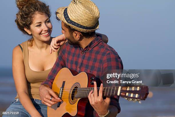 young couple, man playing guitar - serenading stock-fotos und bilder