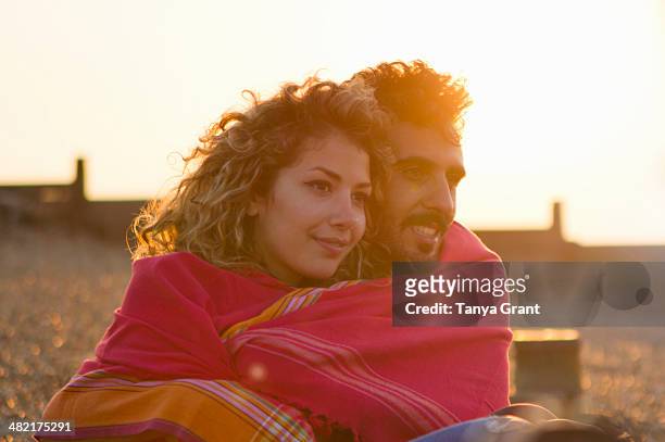 young couple wrapped in towel on beach - woman towel beach stock-fotos und bilder