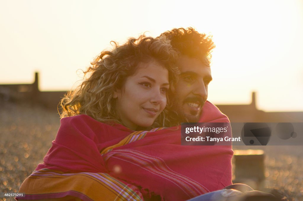 Young couple wrapped in towel on beach