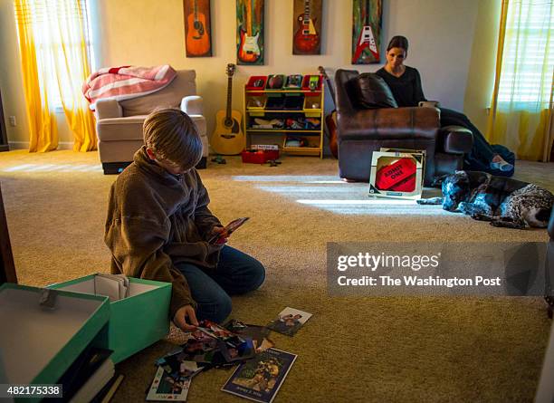 Ethan Prusinski stepson of Jeremy Wise, looks through a box of photos of his late stepfather as his mother and widow, Dana Bernhardt looks on beside...