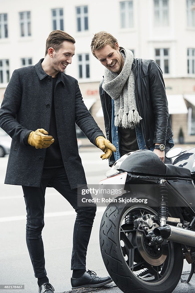Man with friend pointing at motorcycle