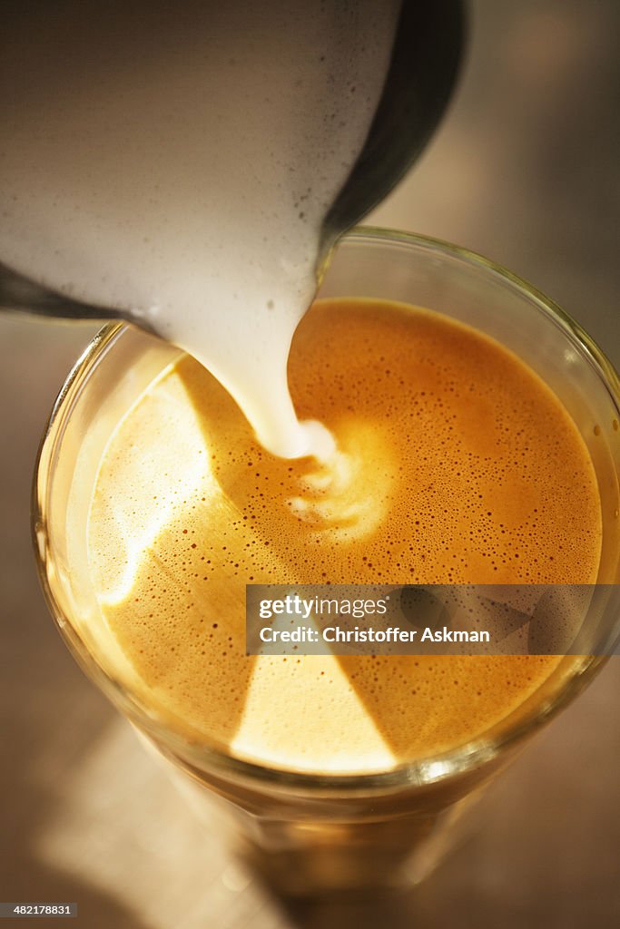 Close up of frothed milk pouring into coffee glass