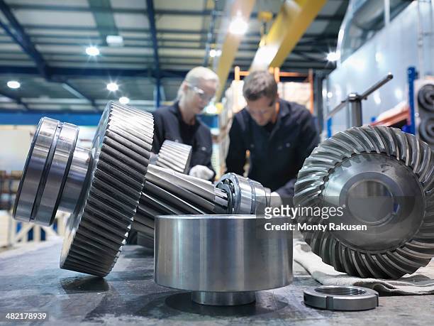 male and female engineers assembling industrial gearbox in engineering factory - engineer gearwheel factory stockfoto's en -beelden