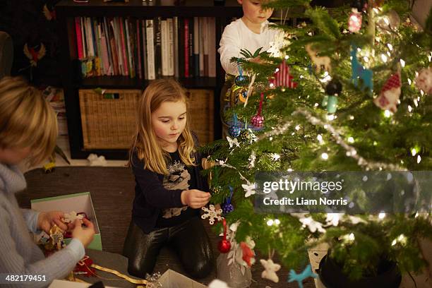 young brother and sister decorating christmas tree - decorating christmas tree stock pictures, royalty-free photos & images