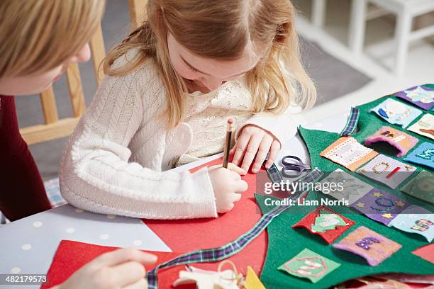 mother and daughter making advent calendar at kitchen table - kids advent stock pictures, royalty-free photos & images