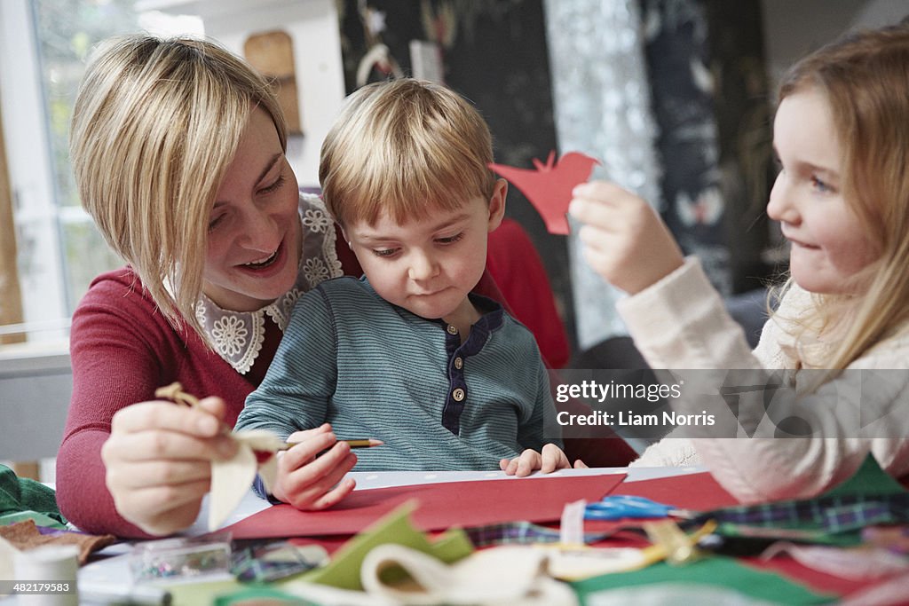 Mother and two children drawing at kitchen table