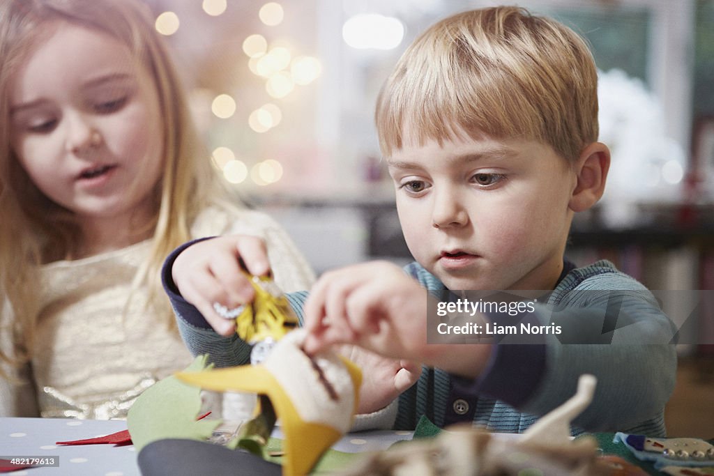 Young brother and sister crafting at kitchen table