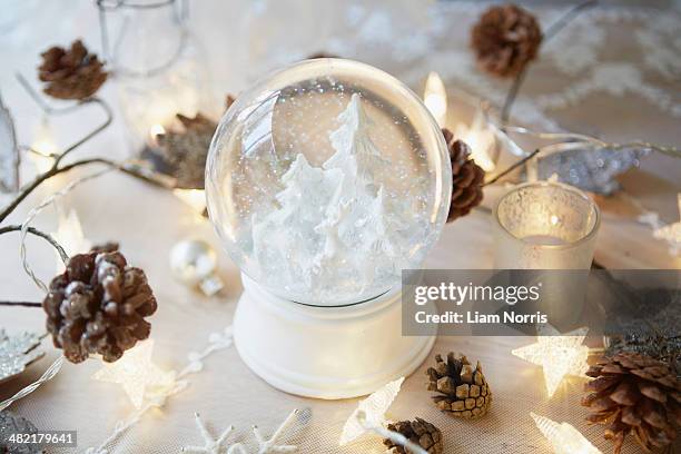 christmas table with snow globe and fir cones - snow globe stock-fotos und bilder