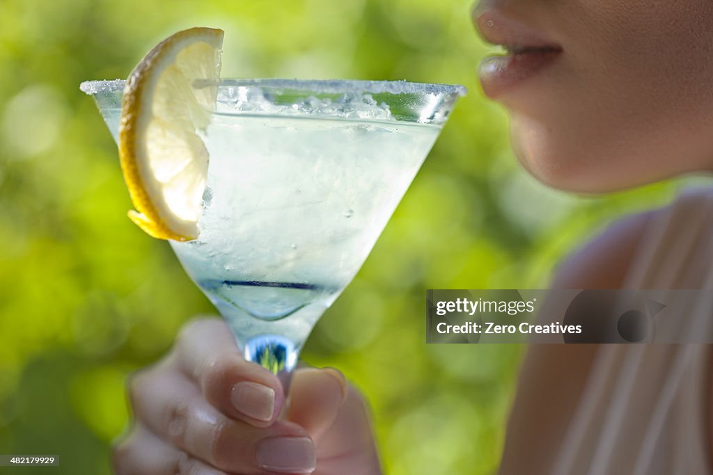 Woman holding glass of margarita to mouth