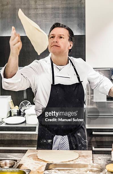 chef throwing pizza dough mid air in commercial kitchen - pizza toss foto e immagini stock