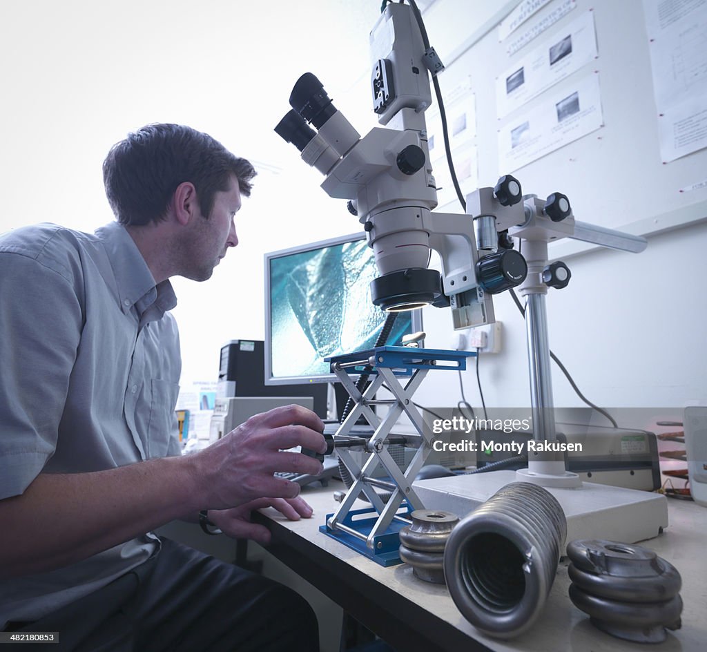 Scientist using microscope to inspect damage to spring