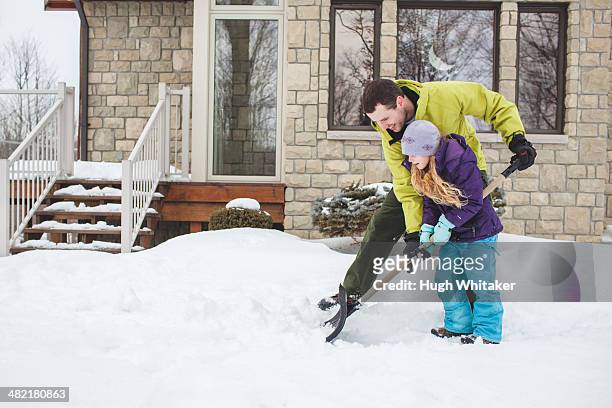 father helping daughter to shovel snow - shoveling snow stock pictures, royalty-free photos & images