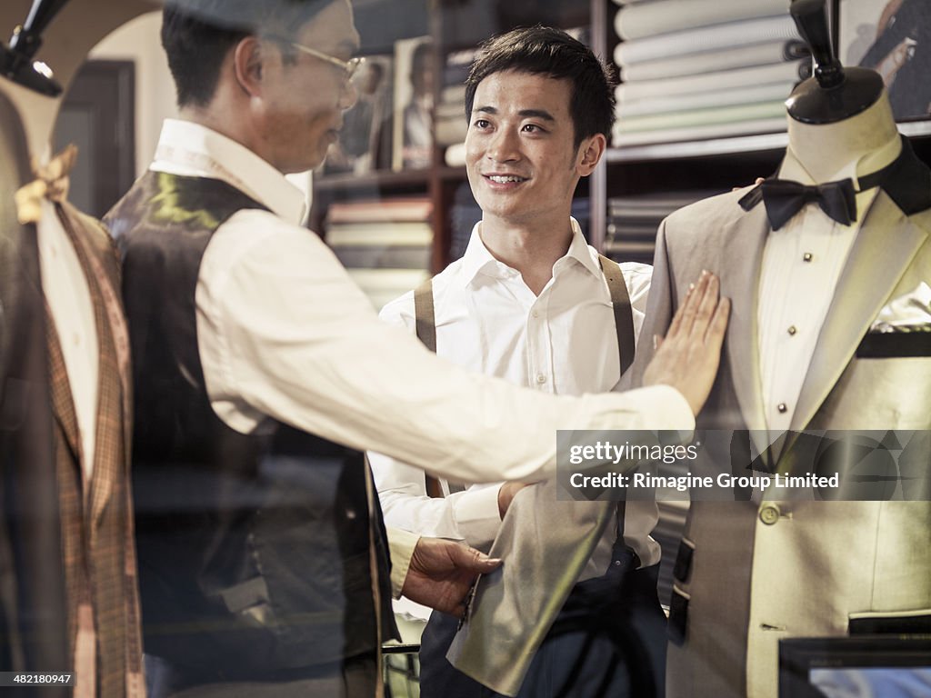 Father teaching son tailoring in family business