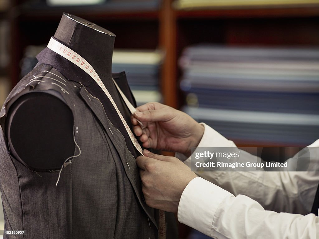 Tailor measuring garment in traditional tailors shop