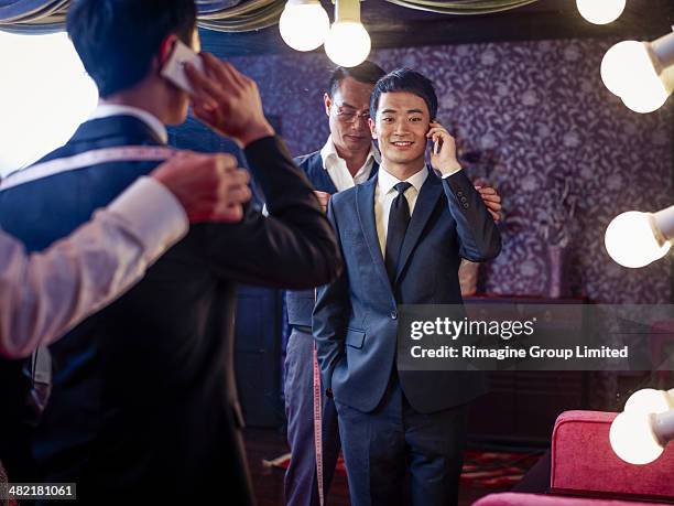 young man trying on suit in traditional tailors shop - maßanzug stock-fotos und bilder