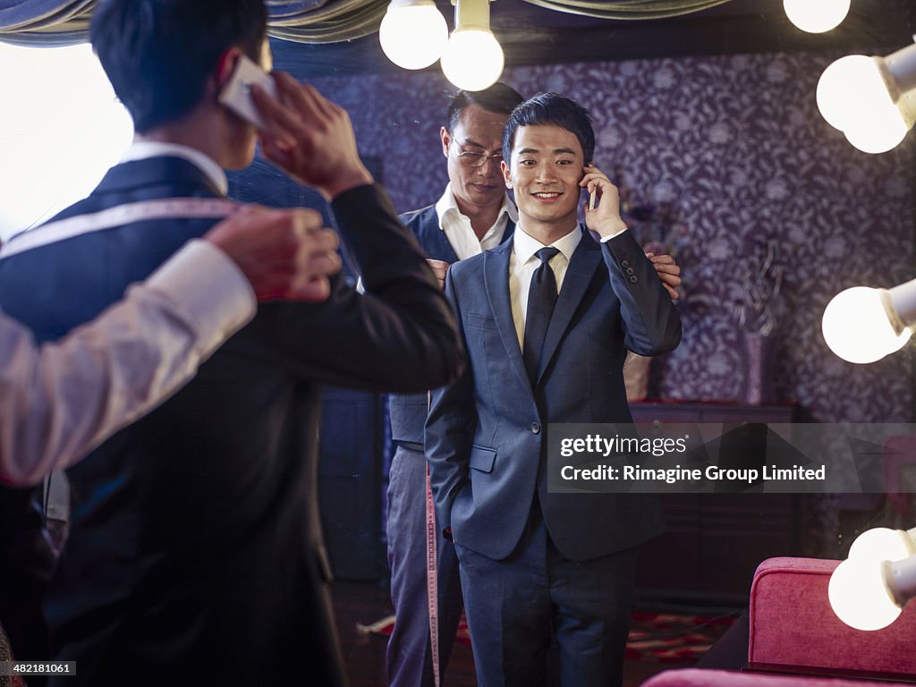 Young man trying on suit in traditional tailors shop