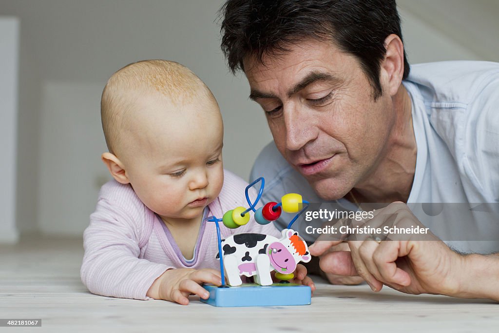 Mature man and baby daughter playing with toy cow