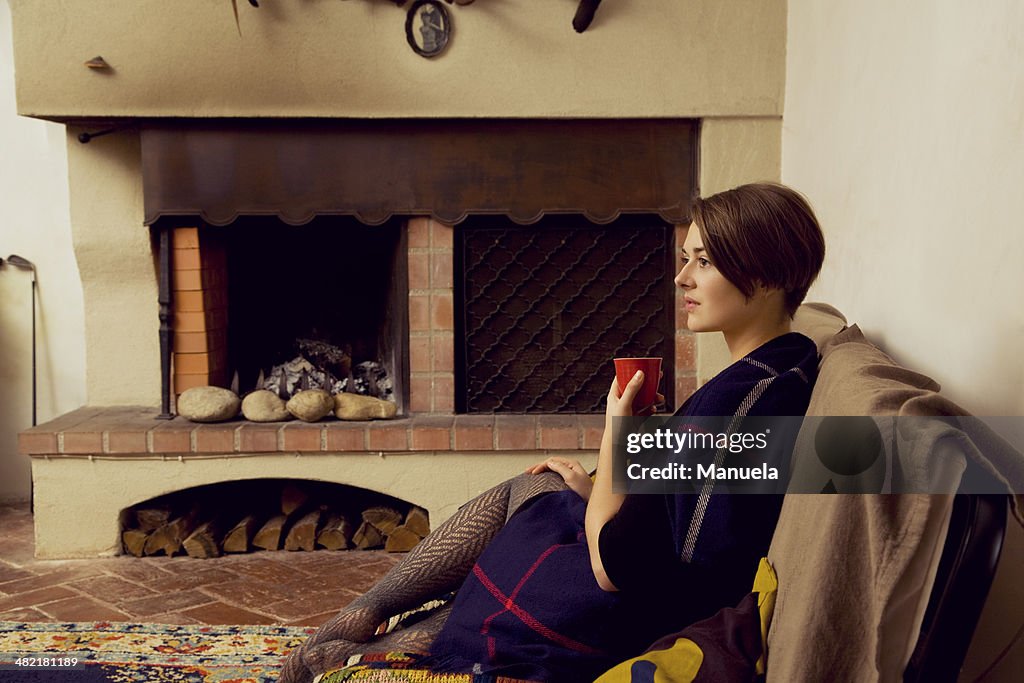 Young woman sitting on sofa wrapped in a blanket