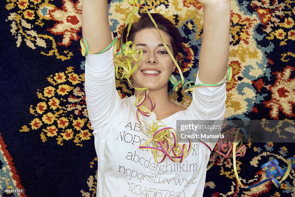 Portrait of young woman and streamers lying on patterned rug