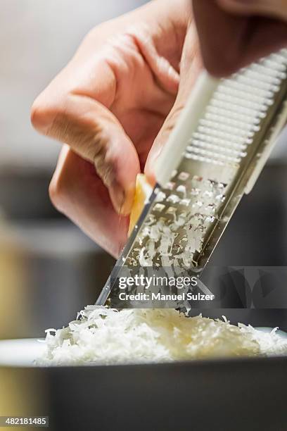 close up of male hand grating parmesan cheese - reiben stock-fotos und bilder