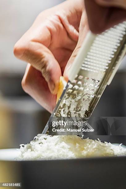 close up of male hand grating parmesan cheese - parmesan fotografías e imágenes de stock