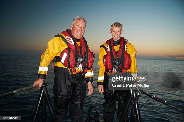 portrait of two men crewing lifeboat at sea - rettungsboot stock-fotos und bilder